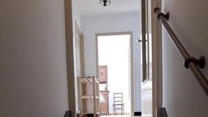 A staircase with a handrail leading to a room with a door, a chair, and a cabinet. - seasonal rental of a villa in the countryside (Meynes)
