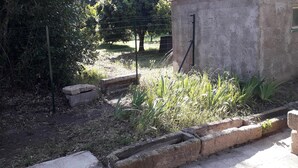 A garden area with a concrete structure, a wire fence, and some plants. - seasonal rental of a villa in the countryside (Meynes)