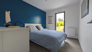 Et soveværelse med en seng, et natbord, et skrivebord med en model af et skib, et vindue med udsigt til grønne omgivelser, og en radiator.
