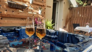 Een bubbelbad met twee champagneglazen, omgeven door houten wanden en potplanten.