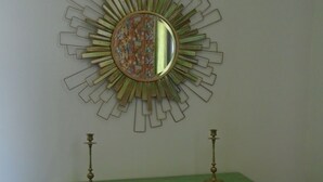 A green desk with two brass candlesticks and a mirror with a sunburst design.