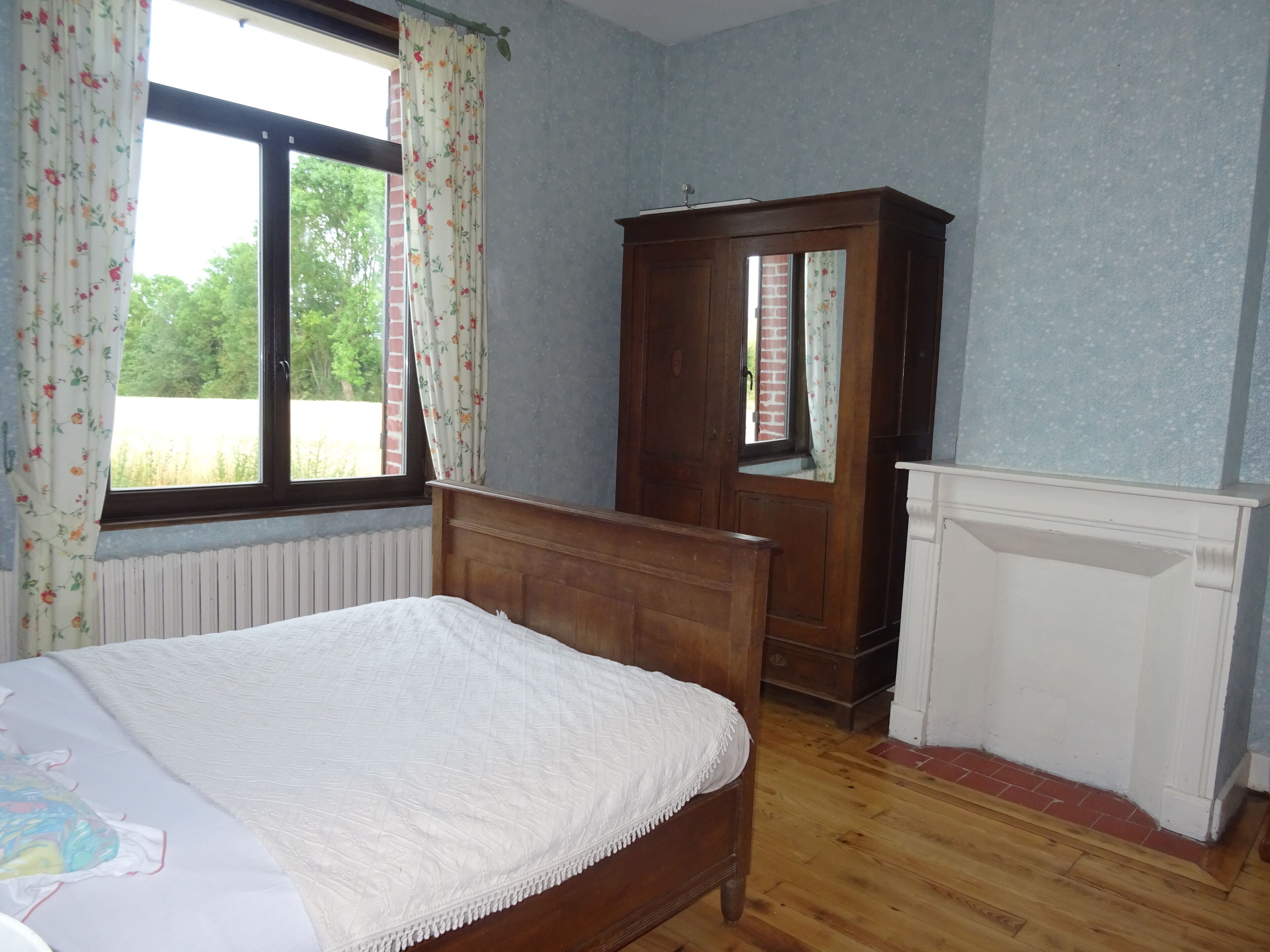 Une chambre à coucher avec un lit en bois, une armoire et un radiateur.