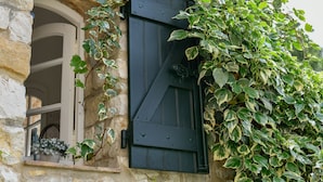 Un bâtiment en pierre avec une porte en bois sombre, en partie recouverte de lierre vert.