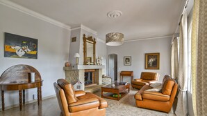 Un salon avec des canapés en cuir, une table basse, une cheminée et un grand miroir.