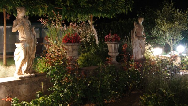 Ein Garten mit Statuen und Blumentöpfen.