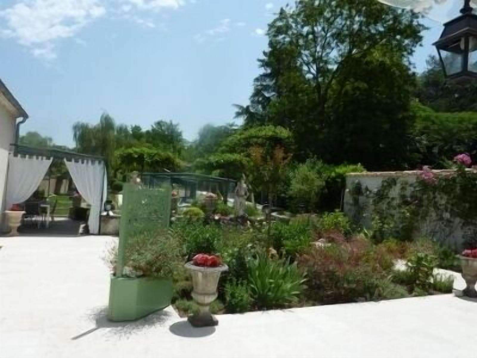 Een patio met een pergola, tuinmeubels en diverse potplanten.