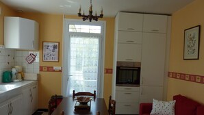 Eine kleine Küche mit Esstisch, Stühlen, einem roten Sofa und einer Küchenzeile.