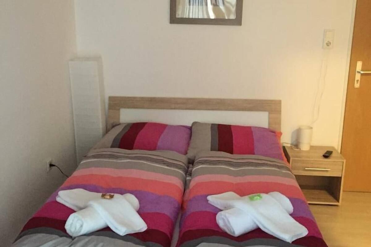 A double bed with striped bedding and two towels.
