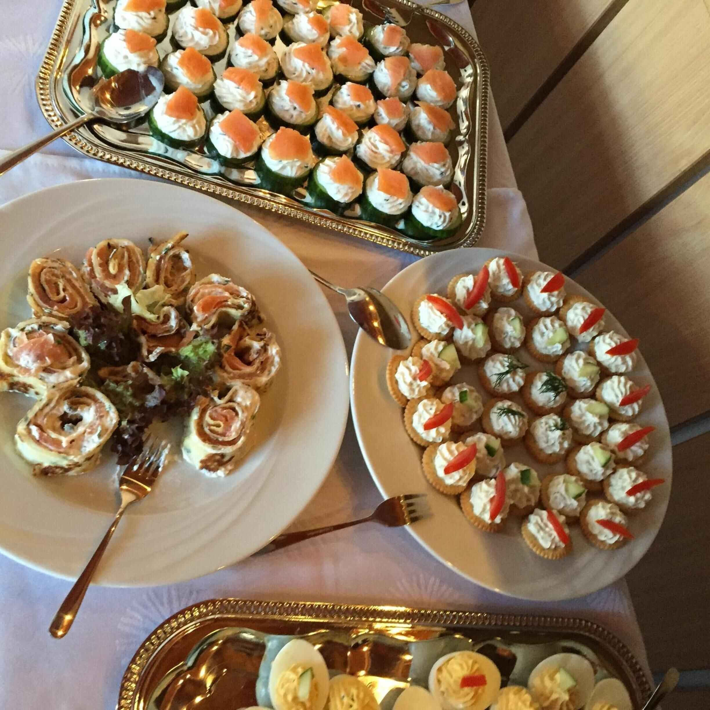 A table with three plates of appetizers, including sushi rolls and other small dishes.