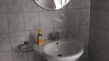 Un baño con un lavamanos blanco, un espejo redondo y un armario debajo.