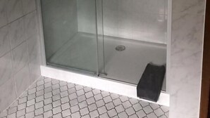 A glass-enclosed shower with a handheld showerhead and a floor-mounted faucet. - Gaststätte und Pension Frankenstube (Nidda)