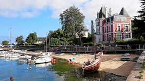 Um porto com barcos, um edifício vermelho grande com torres e uma parede de pedra.