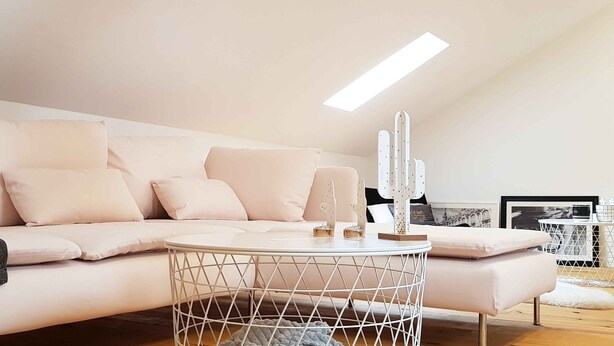 Ein stilvolles Wohnzimmer mit einem weißen Sofa, einem runden Couchtisch und einer Kaktusskulptur.