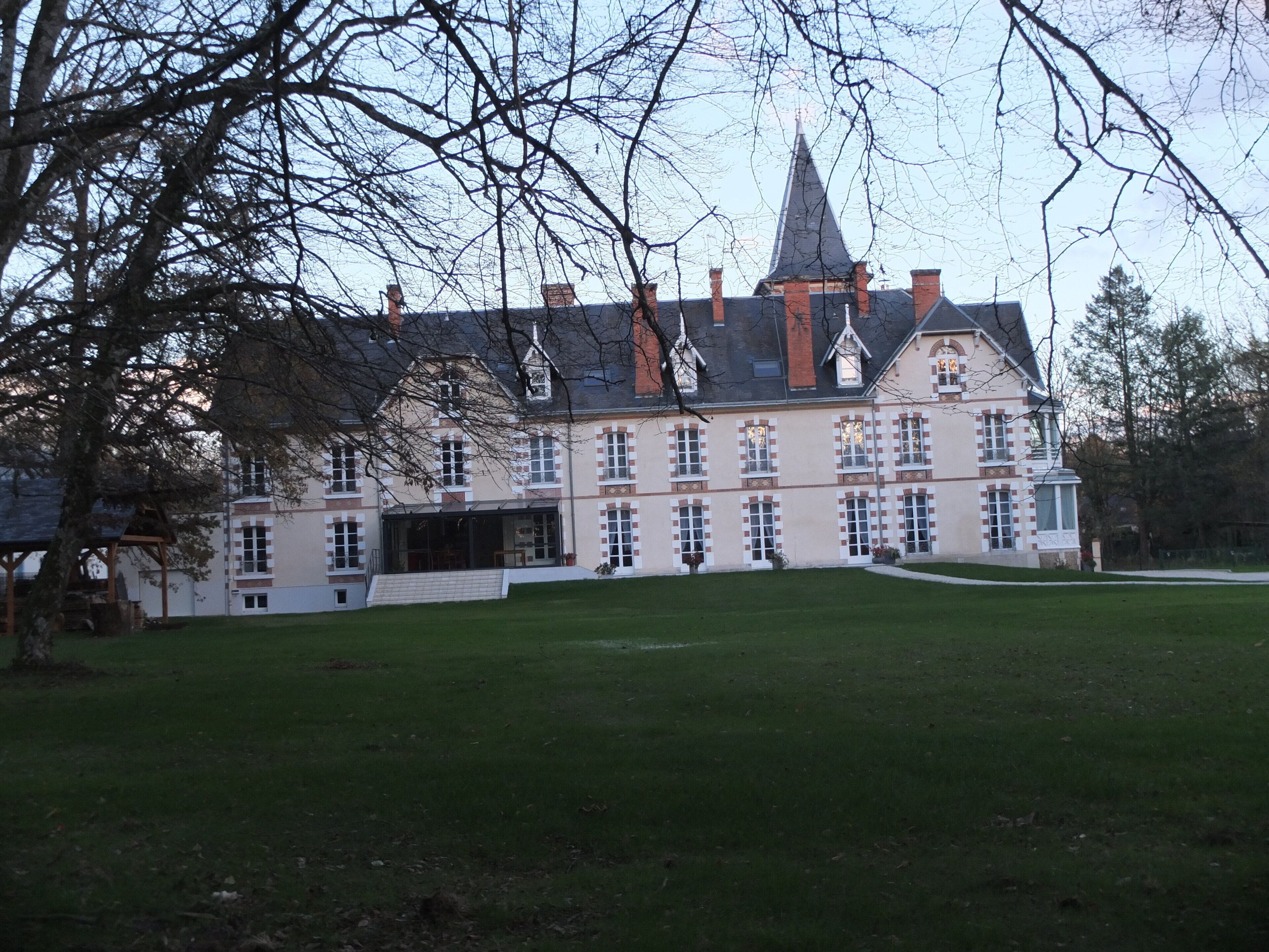 A large, historic building with a symmetrical facade, multiple chimneys, and a prominent tower.