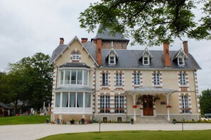 A large, multi-story building with a prominent bay window and a wrap-around porch. - T3 duplex in castle in Sologne (Neuvy-Sur-Barangeon)