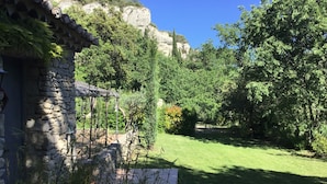 A stone building with a tiled roof, surrounded by lush greenery and a clear blue sky. - Cottage 2 pers.Pets welcome, quiet location, south facing.  Swimming pool. (LE BEAUCET)