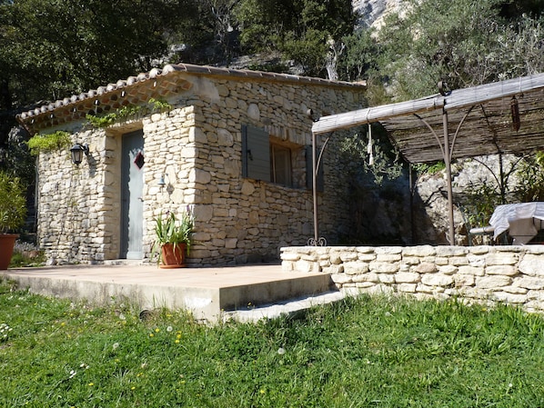 A stone building with a tiled roof, a small porch, and a covered outdoor seating area.