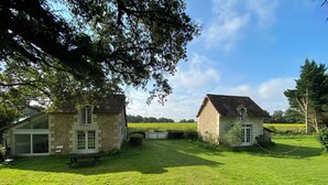 Une maison en pierre avec une grande fenêtre et un banc dans la cour.
