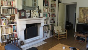 Un salon avec une cheminée, des étagères à livres, un téléviseur et un fauteuil.
