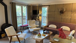 A cozy living room with a fireplace, a sofa, a chair, and a coffee table with decorative items. - Arcs 2000, new 95m² apartment in a chalet, 2 min from the slopes, wifi, pkg (Bourg-Saint-Maurice)