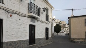 Un carrer estret amb edificis blancs, portes negres i base de pedra.