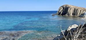 A coastal scene with clear blue waters, rocky cliffs, and a small building on the shore. - Typical house with patio in ALMERIA Andalusia. 4 people in peace. (Almeria)
