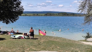 A lakeside picnic area with picnic tables and a flag.