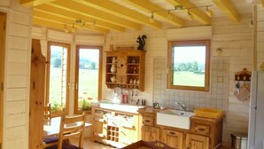 A rustic kitchen with wooden cabinets, a sink, and a window overlooking a garden.