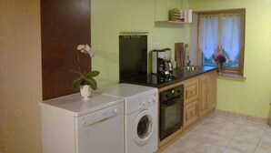 Una cucina compatta con lavatrice, forno e macchina da caffè.