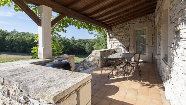 A covered patio with stone walls, a grill, and outdoor furniture. - Character house in the countryside. (Les Arques)