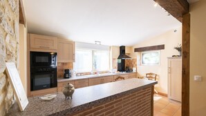 A kitchen with a granite countertop, a brick backsplash, and wooden cabinets. - Character house in the countryside. (Les Arques)