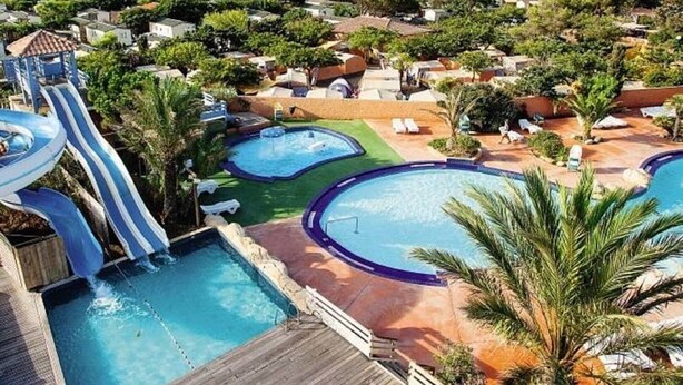 A resort with multiple swimming pools, a water slide, and a view of the surrounding landscape. - New mobile home (6/8 pers.), All options, Camping Marestang 4 * Location 23 (Canet-en-Roussillon)