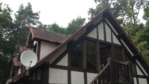A traditional half-timbered house with a steeply pitched roof, a satellite dish, and a wooden staircase leading to the entrance. - Studio in a park near Chambord (ST LAURENT NOUAN)