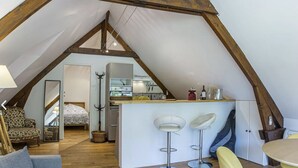 A loft-style apartment with a kitchen, two bar stools, a dining table, and a sofa. - Studio in a park near Chambord (ST LAURENT NOUAN)
