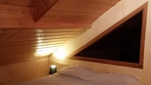 A bedroom with a sloped ceiling, a bed, and a window. - Comfortable, quiet chalet (Les Adrets)
