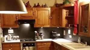 A kitchen with wooden cabinets, a stove, a sink, and a dining table. - Comfortable, quiet chalet (Les Adrets)