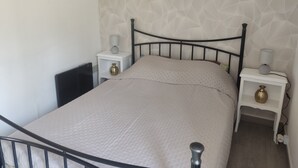 A bed with a metal frame, white nightstands with lamps, and a geometric patterned wall. - MAISONETTE T2 30 M2 (Carpentras)
