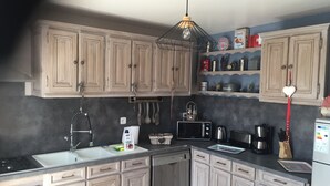 A kitchen with light wooden cabinets, a stainless steel dishwasher, a microwave, and a sink.