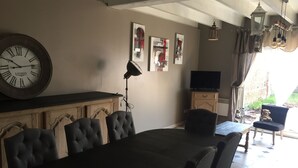 A dining area with a wooden table and chairs, a large wall clock, and artwork.