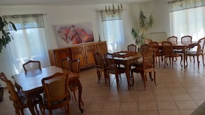 A dining area with a large wooden table surrounded by wicker chairs, a chandelier, and a large painting on the wall. - Cante Grillet in Provence at the foot of the Luberon LACOSTE (84480) Chambre FLORY (LACOSTE)