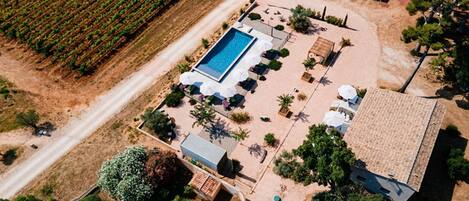 An aerial view of a property with a swimming pool, outdoor seating, and a garden.
