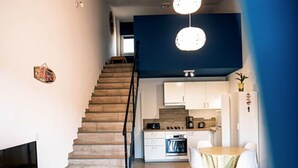 Un appartement moderne doté d’un escalier en bois, d’une cuisine, d’un coin repas et d’un salon avec une télévision et un tapis bleu.