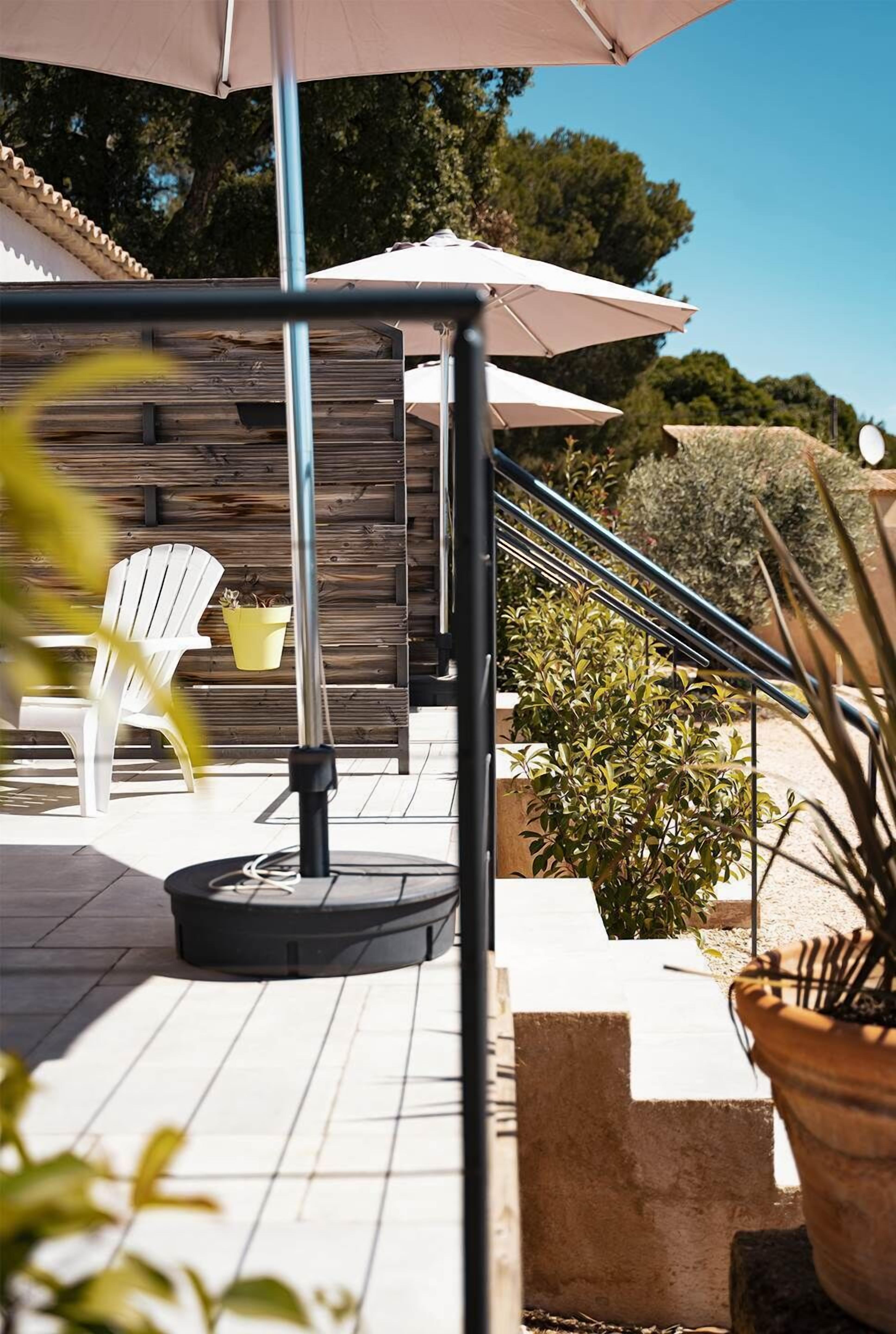 An outdoor patio area with a round table, chairs, and umbrellas.
