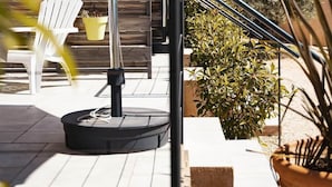 Une terrasse avec des meubles d’extérieur, un mur en bois et des plantes en pot.