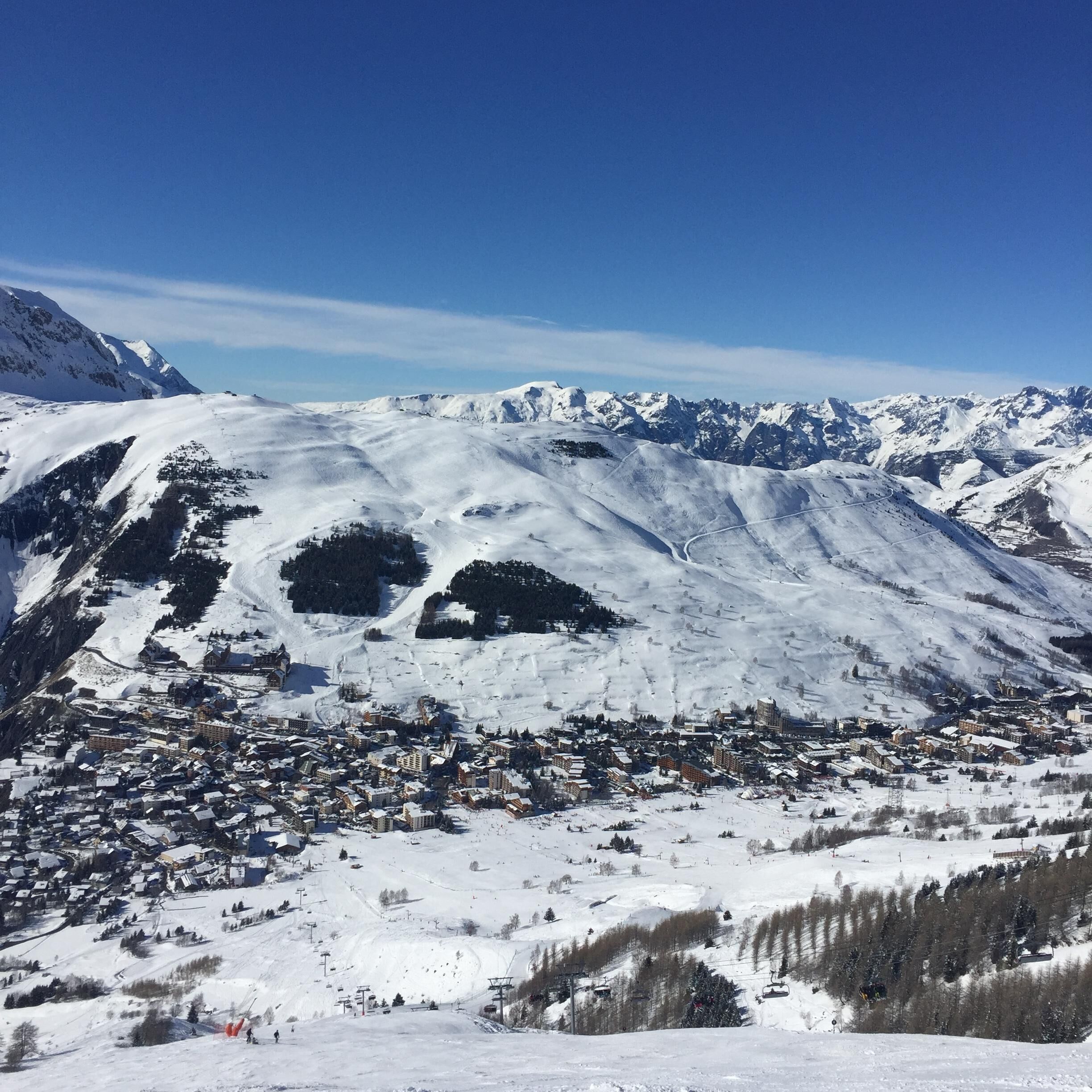 A snow-covered mountain town with a mix of residential and commercial buildings, ski slopes, and a clear blue sky.