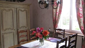 Ein Essbereich mit einem Tisch für vier Personen, einer Blumenvase, einer Chandelüster und einem Fuchs an der Wand.