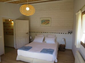 A bedroom with a bed, a hanging light fixture, a door, and a wall with a decorative border.