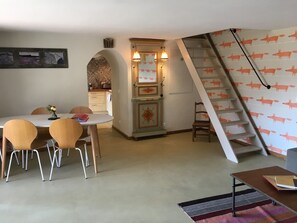 A dining area with a table and chairs, a decorative cabinet, a staircase with a unique design, and a wall with a pattern.