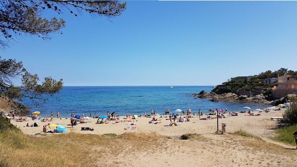 A beach with people sunbathing and swimming, clear blue water, and buildings in the background. - 3P RDJ air-conditioned apartment in residence with swimming pool and tennis court in St Aygulf (Unknown)
