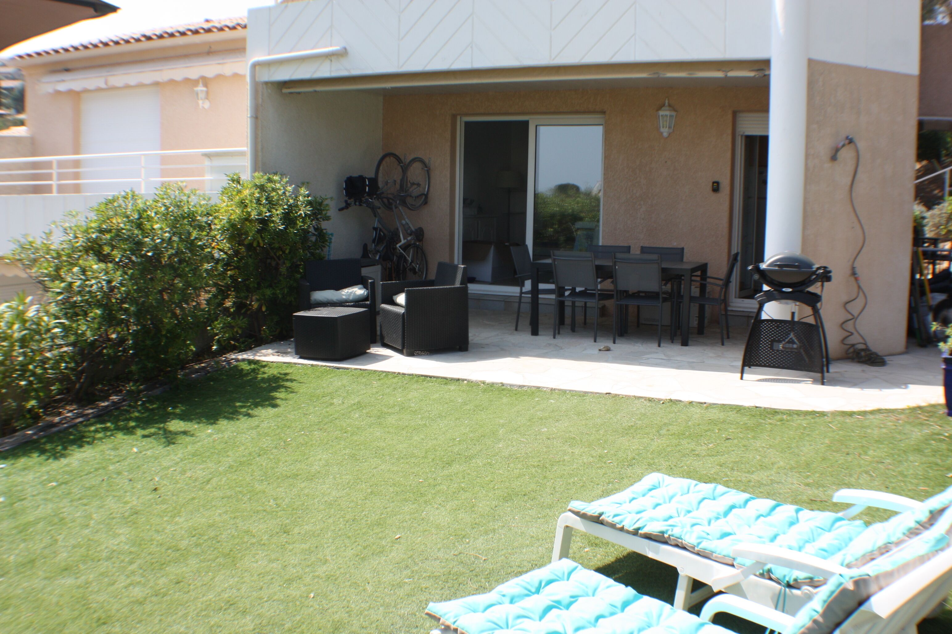 Eine Terrasse mit Gartenmöbeln, einem Grill und einem Fahrradständer.